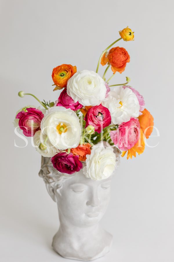 Vertical stock photo of a sculpture toped with colorful flowers.