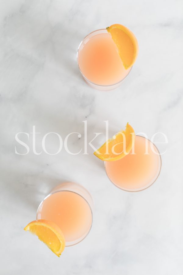 Vertical stock photo of 3 glasses with citrus juice.