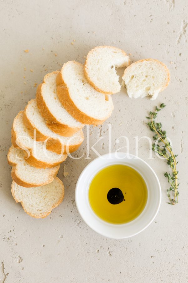 Vertical stock photo of a sliced loaf of bread and olive oil.