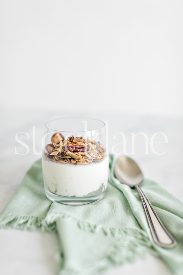 Vertical stock photo of a glass with yogurt and granola.