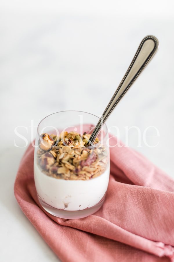 Vertical stock photo of a glass with yogurt and granola.