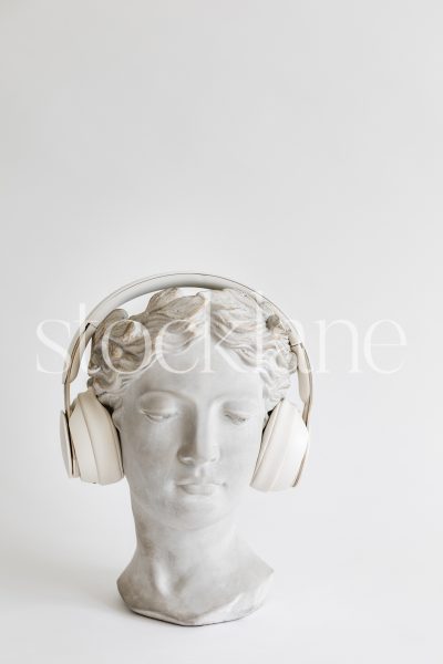 Vertical stock photo of a woman head sculpture with headphones