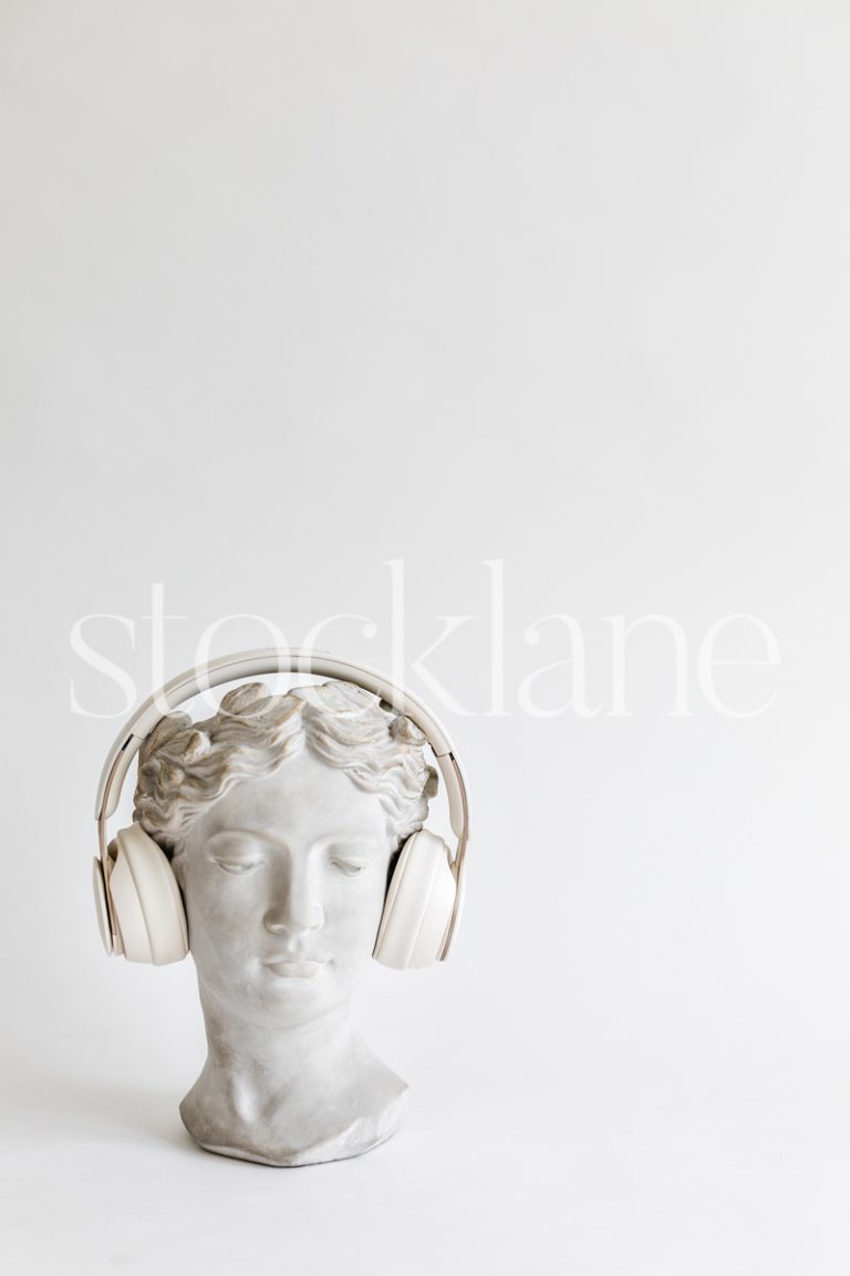 Vertical stock photo of a woman head sculpture with headphones