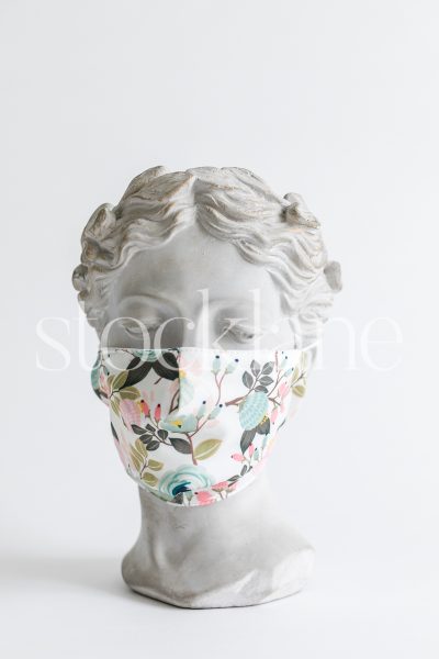 Vertical stock photo of a woman head sculpture with a floral mask.