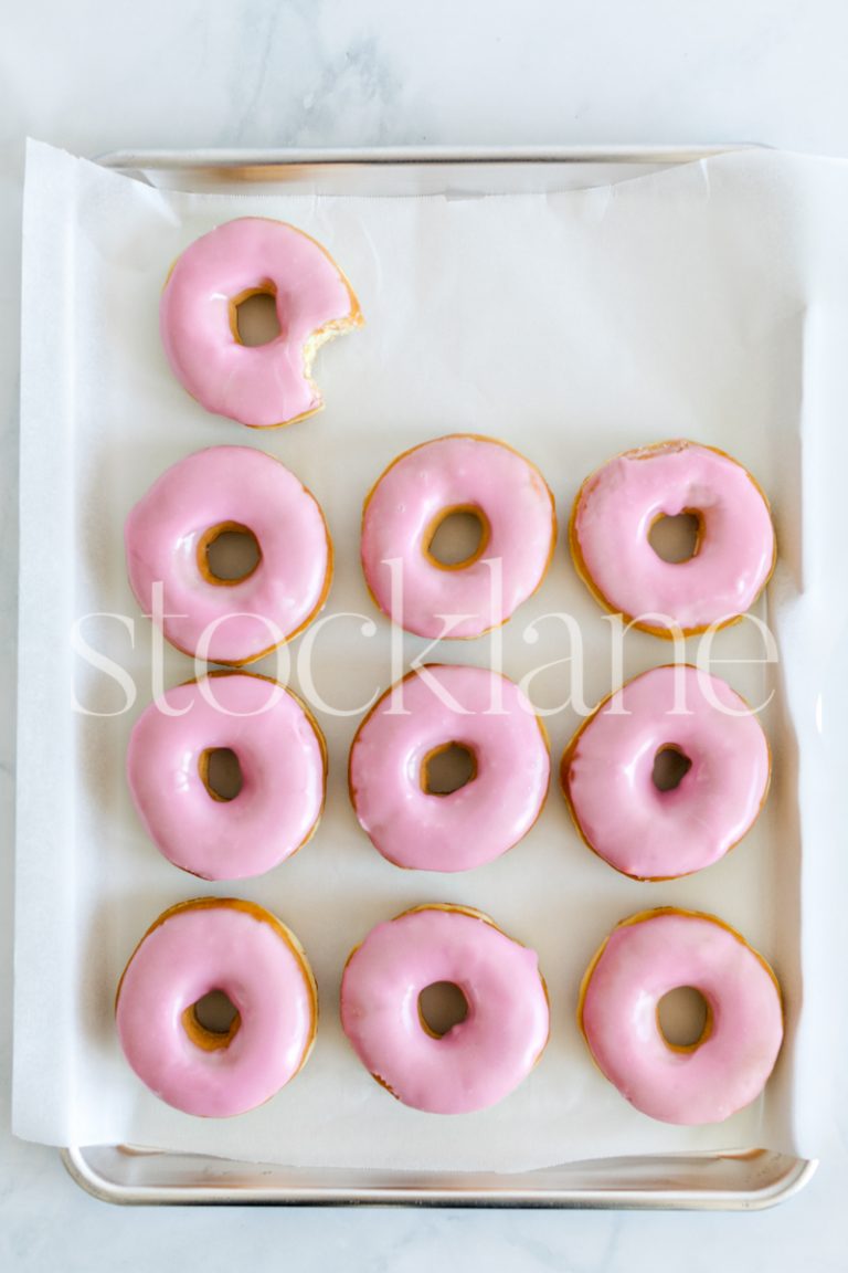 Vertical stock photo of a tray with a pink donuts.