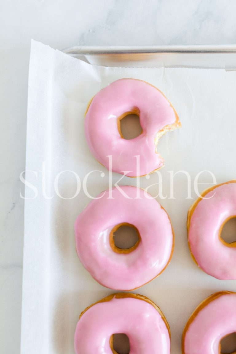 Vertical stock photo of a tray with a pink donuts.