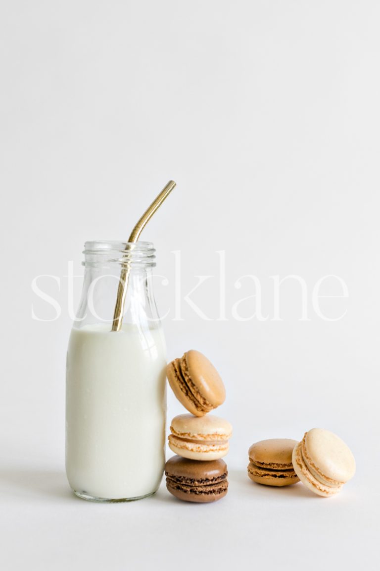 Vertical stock photo of a milk bottle and macarons.