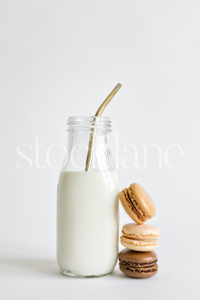 Vertical stock photo of a milk bottle and macarons.