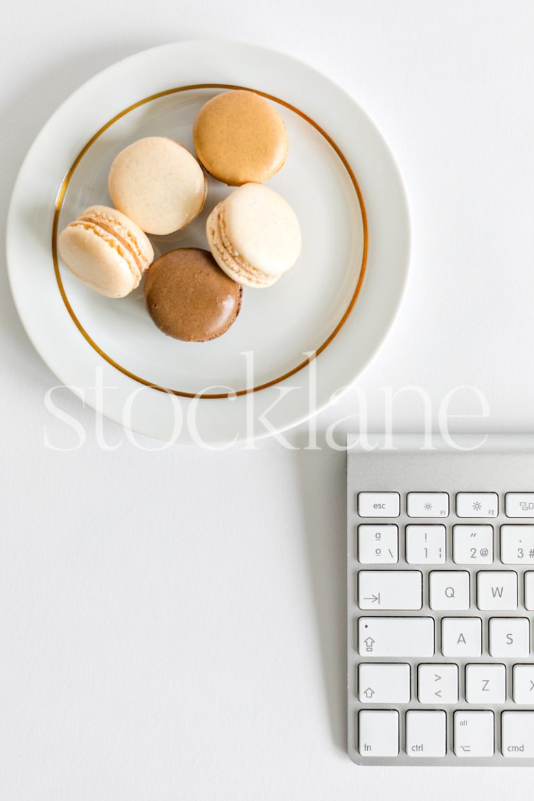 Vertical stock photo of a plate with macarons and a keyboard.