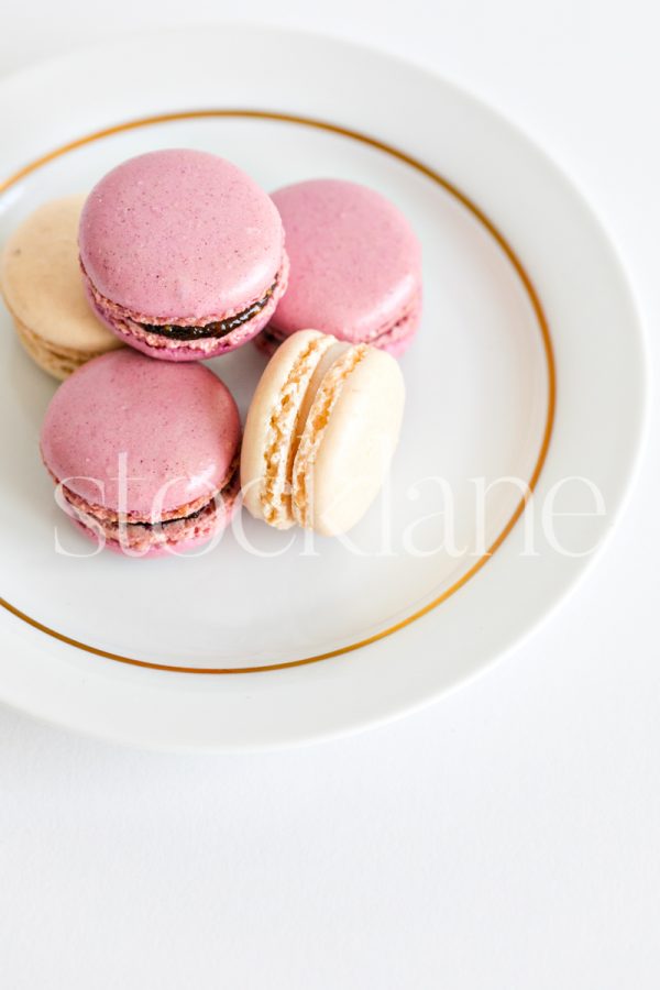 Vertical stock photo of a plate of pink and cream macarons.