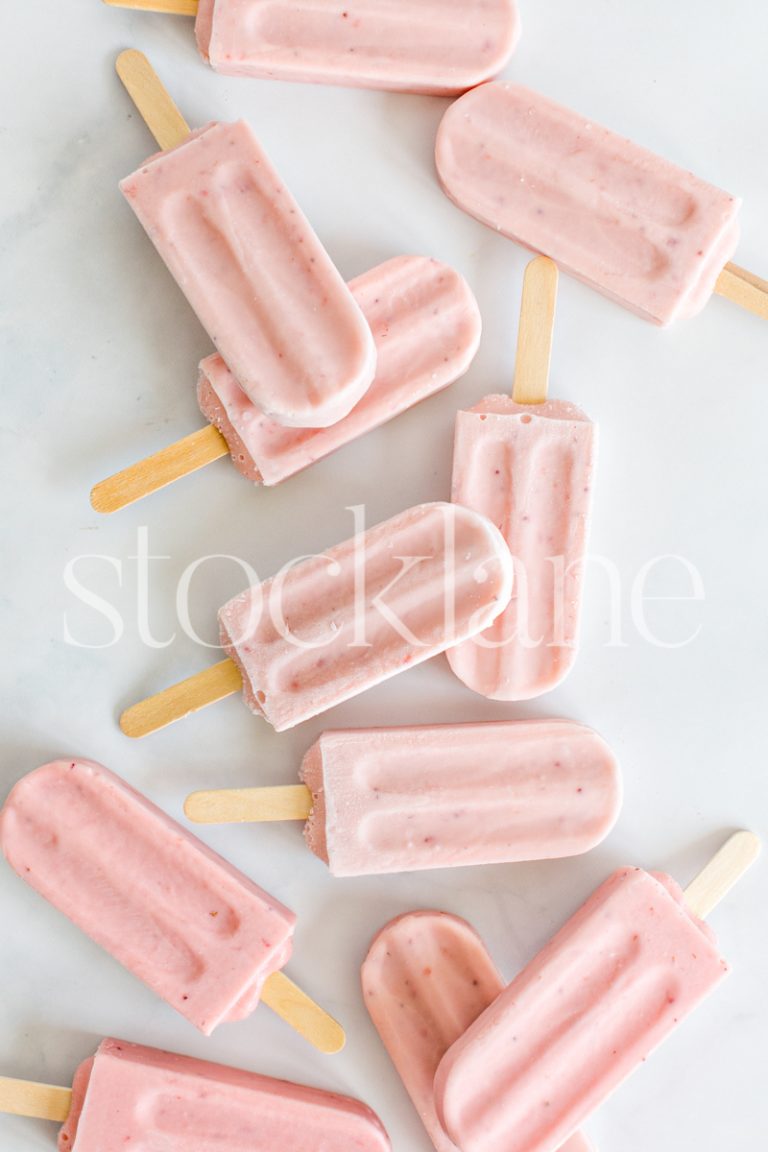 Vertical stock photo of a bunch of strawberry popsicles.