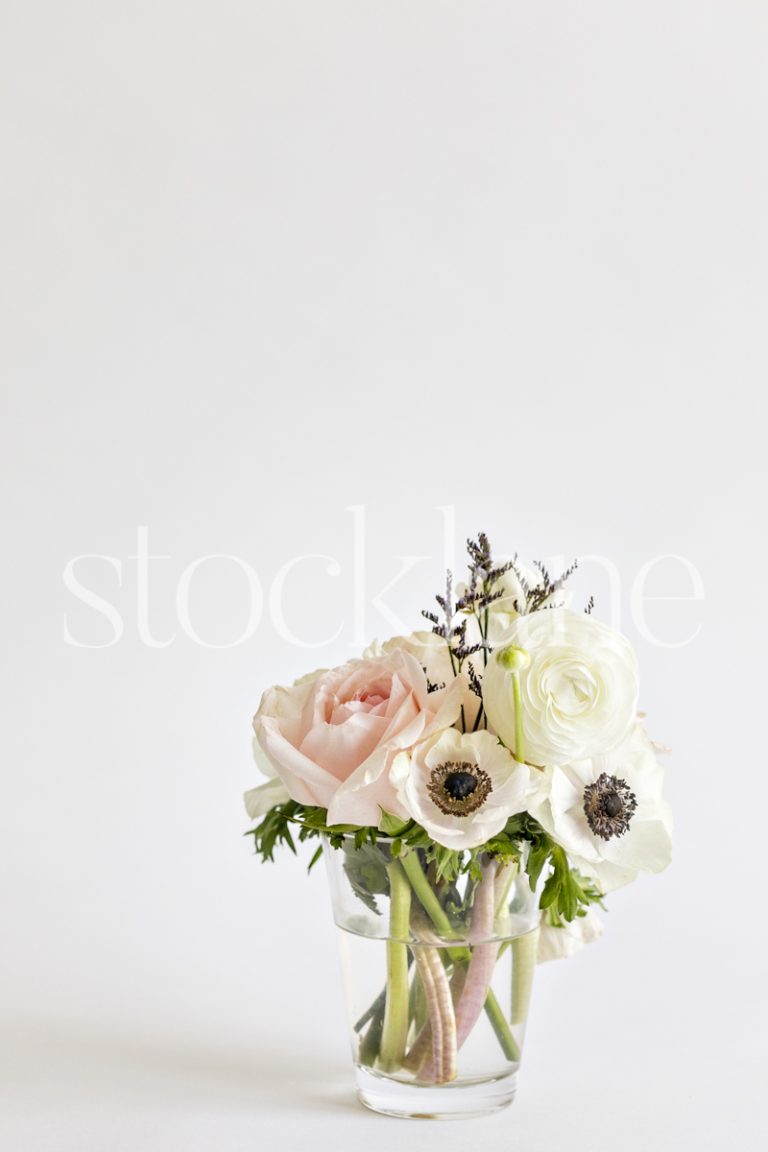 Vertical stock photo of a flower bouquet with pink roses, white anemone and white ranunculus.