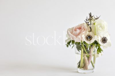 Horizontal stock photo of a flower bouquet with pink roses, white anemone and white ranunculus.