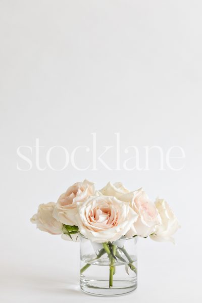 Vertical stock photo of a vase with pink roses.