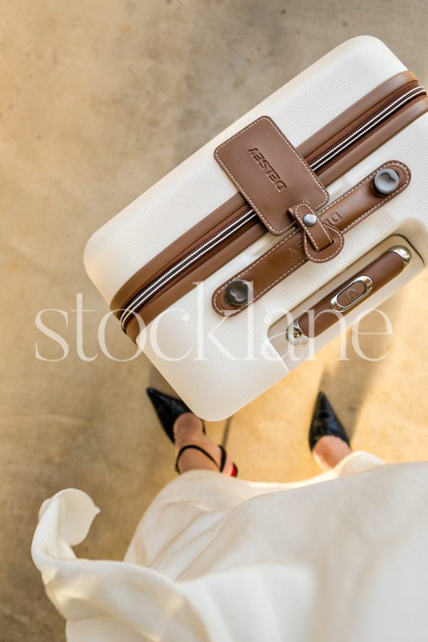 Vertical stock photo of a woman and a suitcase.