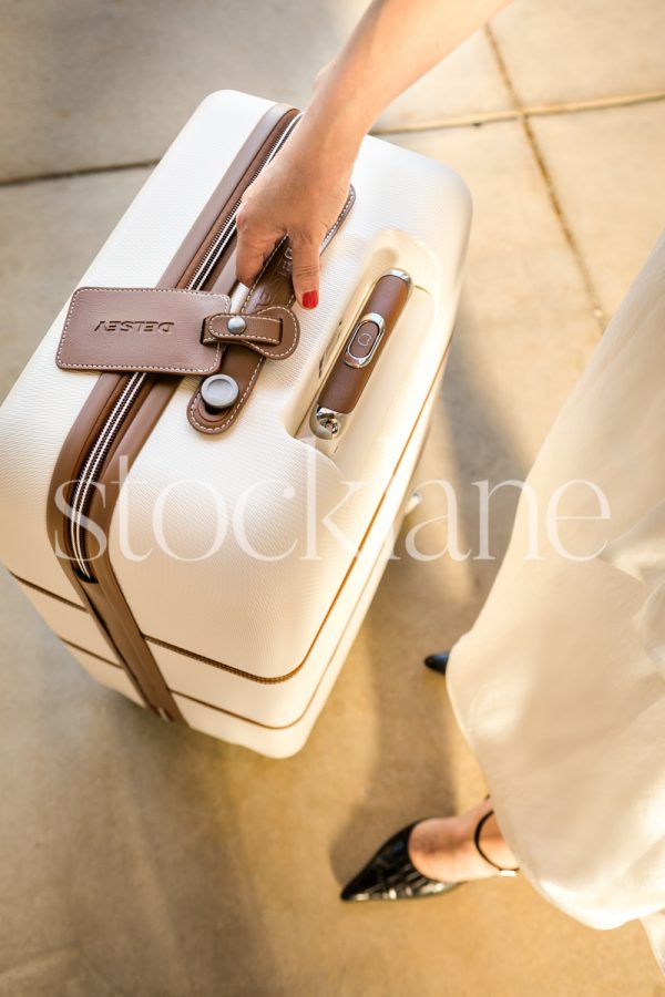 Vertical stock photo of a woman holding a suitcase.