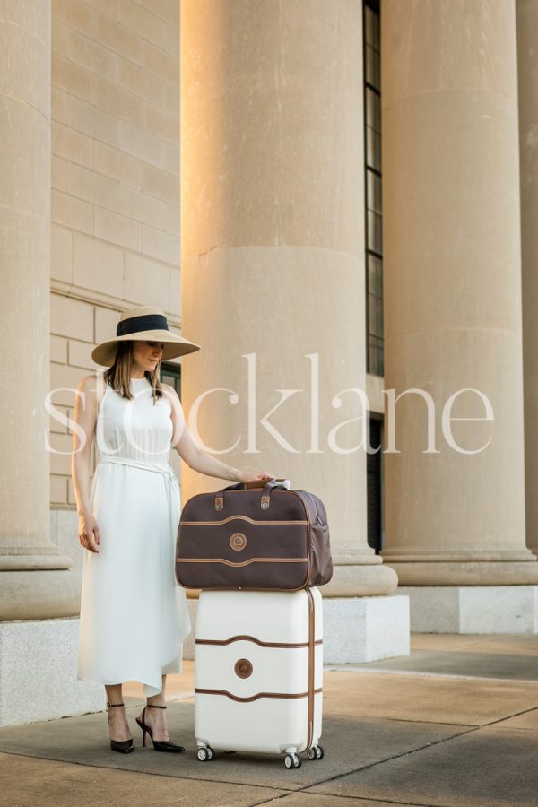 Vertical stock photo of a woman holding a suitcase.