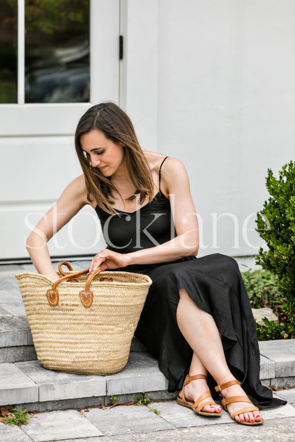 Vertical stock photo of a woman sitting on a doorstep.