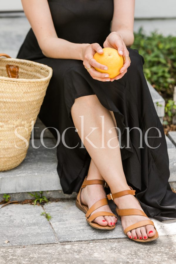 Vertical stock photo of a woman sitting and holding a grapefruit.