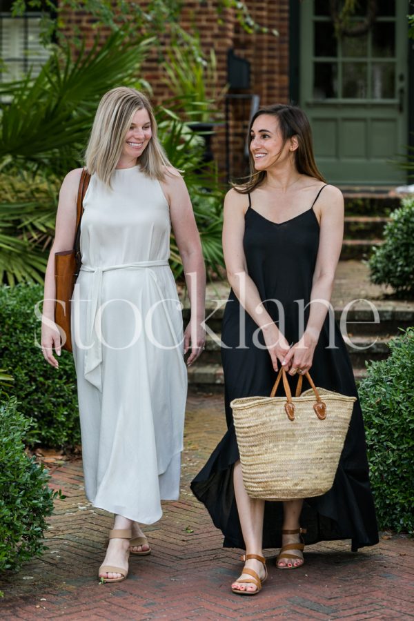 Vertical stock photo of two women chatting in front of a home.