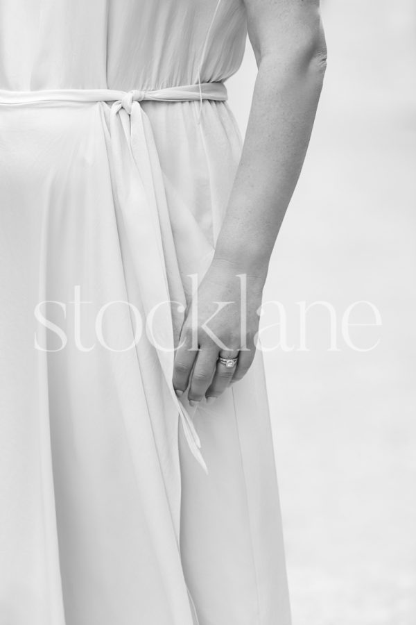 Vertical black and white photo of a woman wearing a white dress.