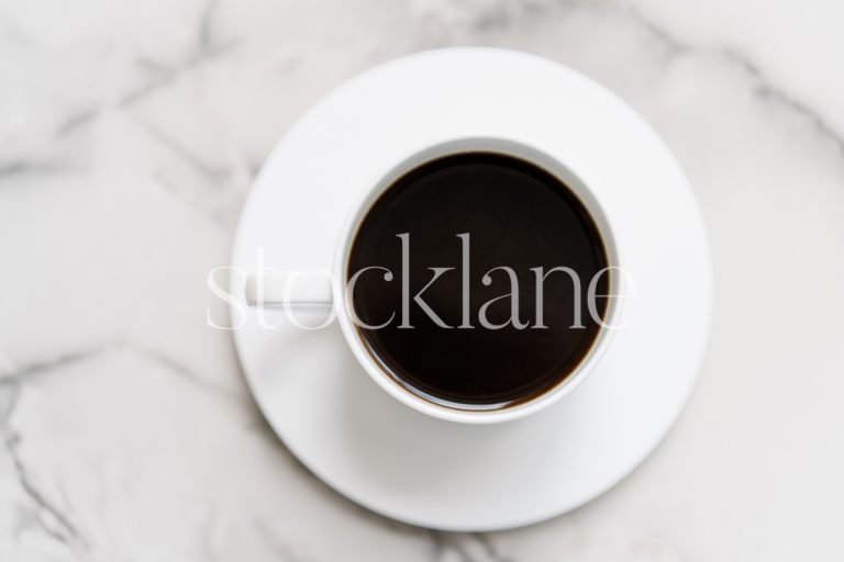 Horizontal stock photo of a marble table top with a cup of coffee.