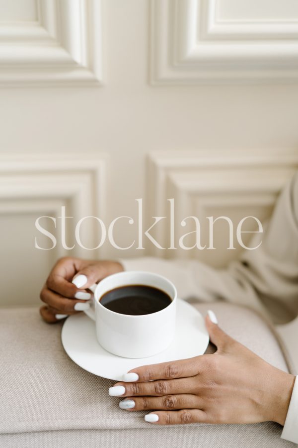 Vertical stock photo of a woman's hands holding a cup of coffee.