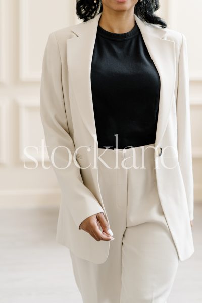 Vertical stock photo of a woman wearing a white suit and a black top.