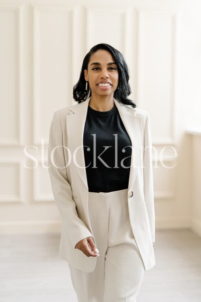 Vertical stock photo of a woman wearing a white suit and a black top.