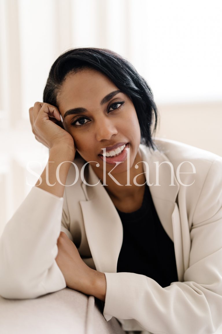 Vertical stock photo of a woman wearing a white suit and black top.