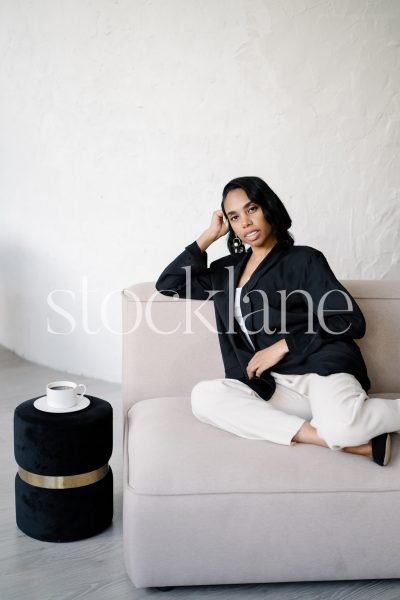 Vertical stock photo of a woman lounging on a pink couch.