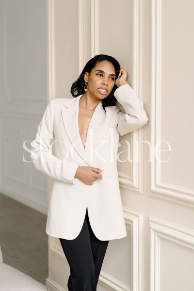 Vertical stock photo of a woman leaning against a wall.