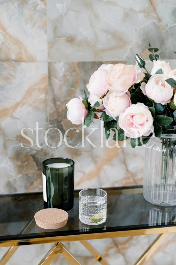 Vertical stock photo of a table with flowers, candle and a drink.