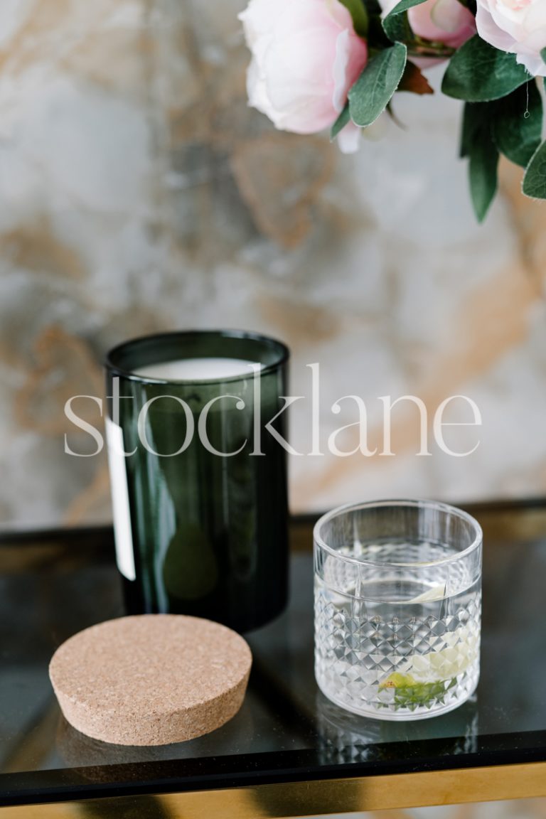 Vertical stock photo of a table with flowers, candle and a drink.