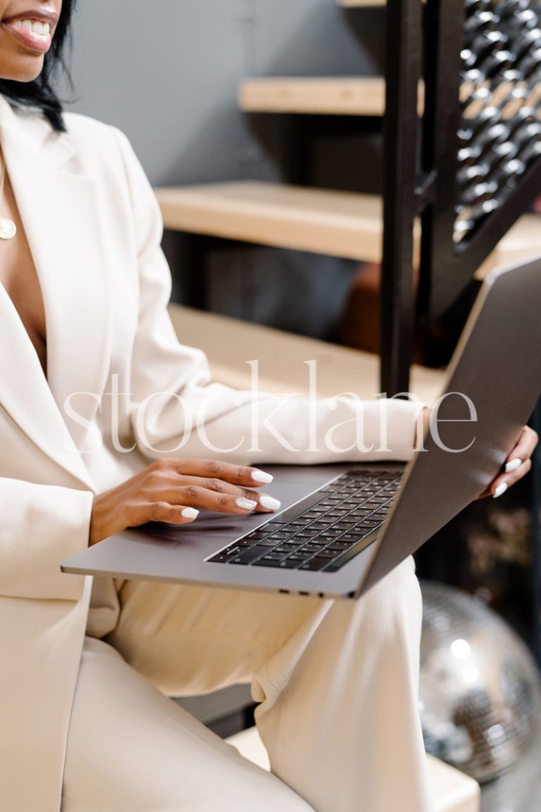 Vertical stock photo of a woman sitting on stairs, working on her laptop.