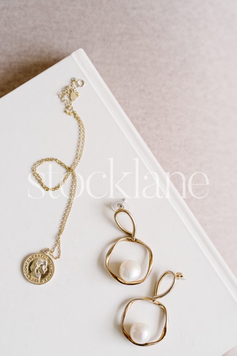 Vertical stock photo of jewelry on a neutral colored notebook.