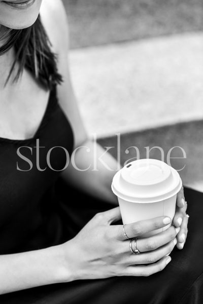 Vertical black and white stock photo of a woman having a cup of coffee.