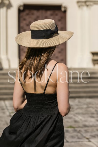 Vertical photo of a woman wearing a black dress and a hat.