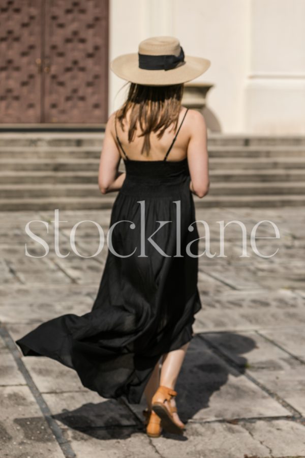 Vertical photo of a woman wearing a black dress and a hat.