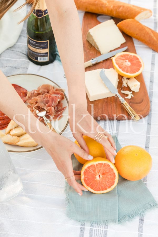 Vertical stock photo of a woman arranging some oranges for a picnic.