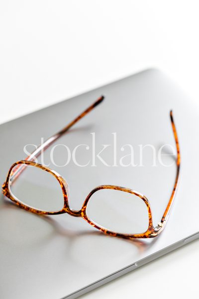 Vertical stock photo of tortoise glasses on a laptop.