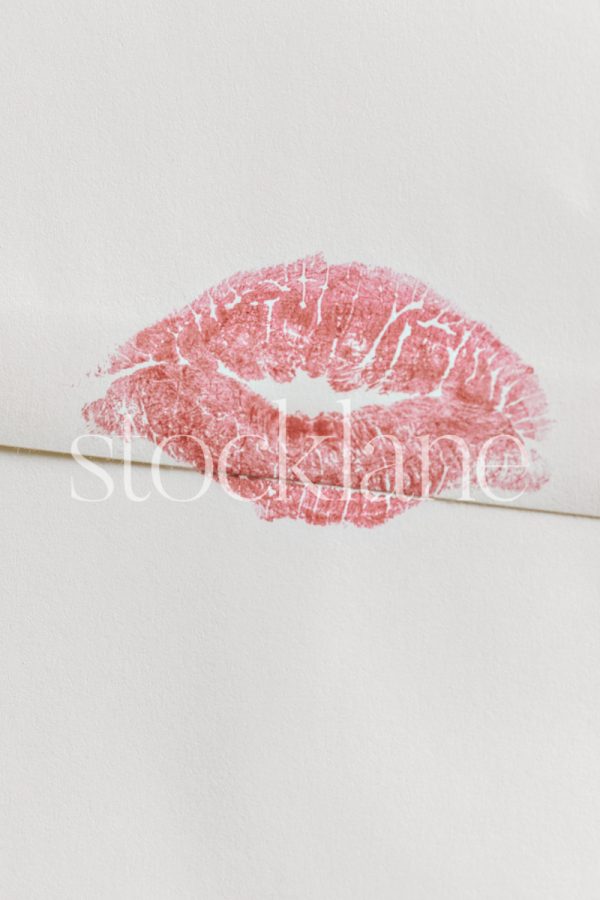 Vertical stock photo of an envelope with a kiss lipstick mark.