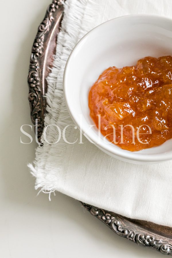 Vertical stock photo of a small bowl with jam on a silver tray.