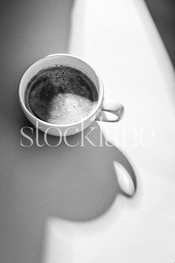 Vertical black and white stock photo of a cup of coffee.