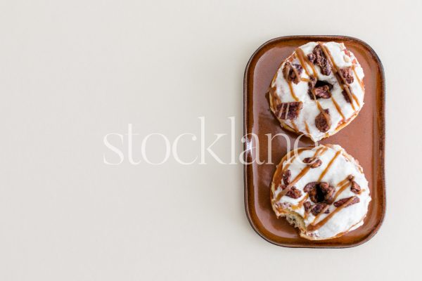 Horizontal stock photo of fall-themed donuts on a plate on a neutral background.