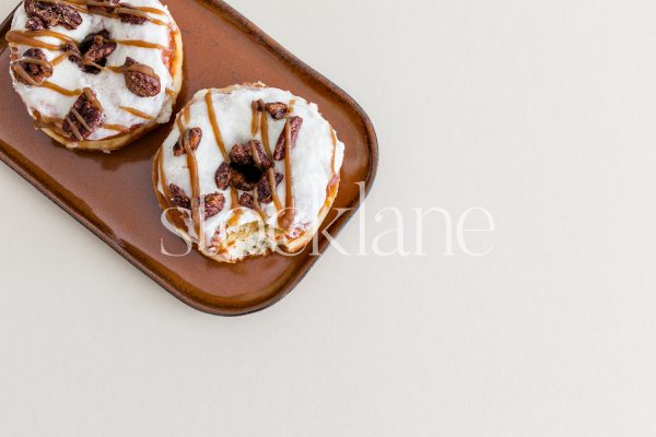 Horizontal stock photo of fall-themed donuts on a plate on a neutral background.