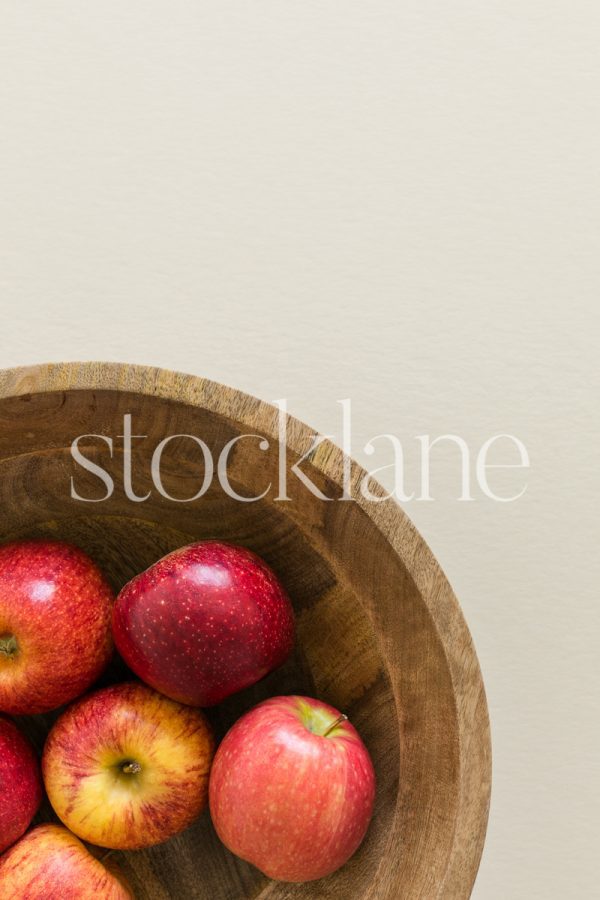 Vertical photo of a bowl of apples on a neutral background.