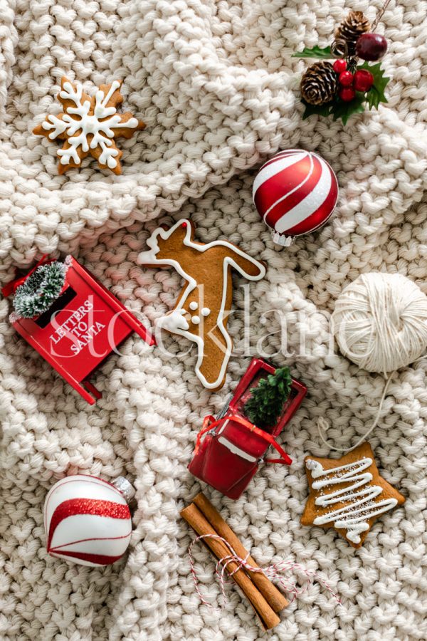 Vertical stock photo of Christmas ornaments and cookies on a blanket.