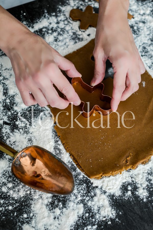 Vertical stock photo of a woman making gingerbread cookies.