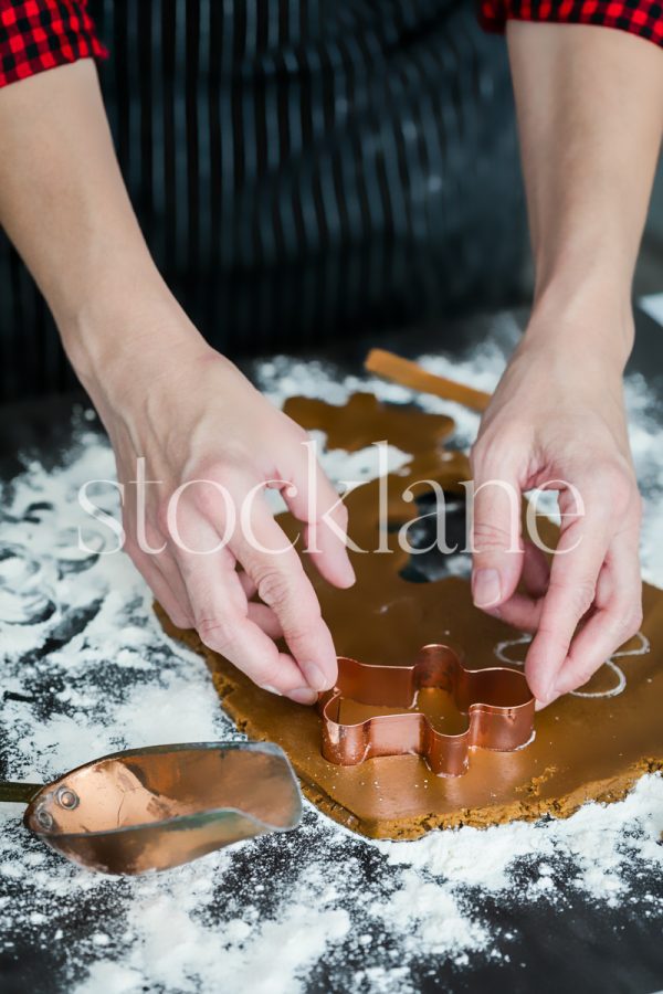 Vertical stock photo of a woman making gingerbread cookies.